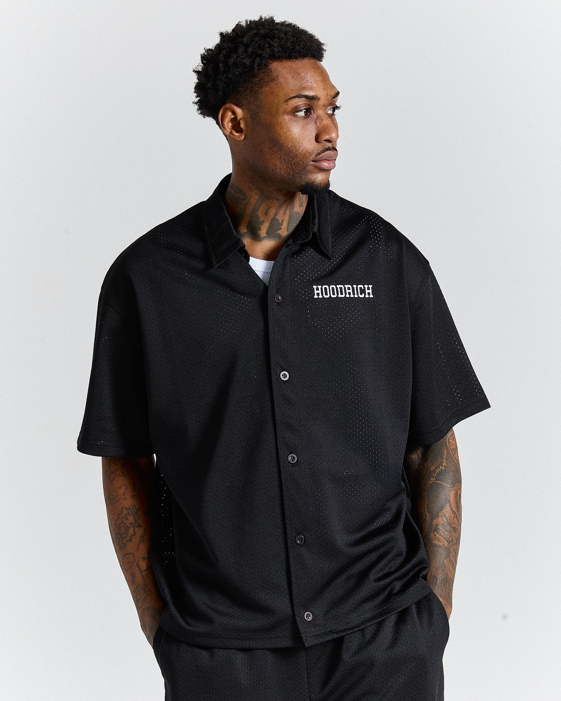 Man wearing a black 'HOODRICH' shirt on a white background