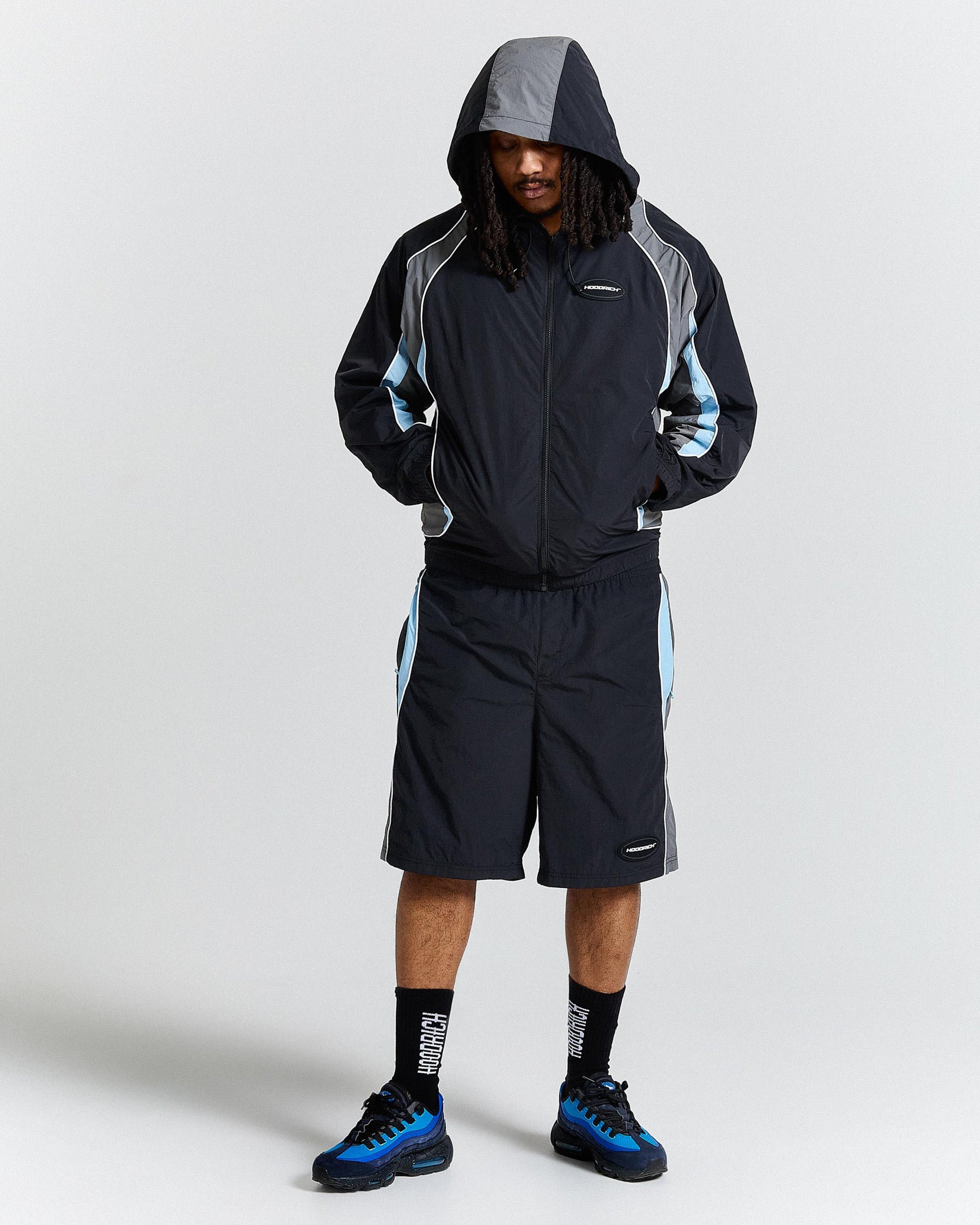 Person wearing a black and grey jacket with blue accents on a white background