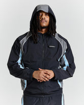 Person wearing a black and gray jacket with a hood on a light gray background