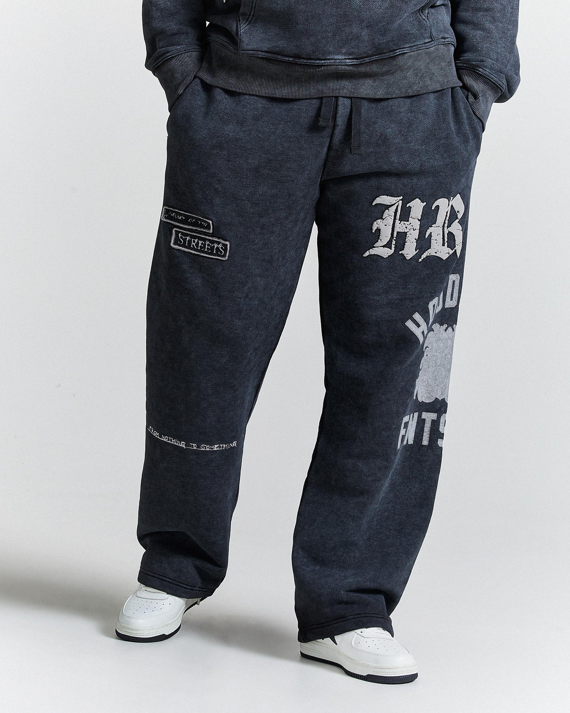Person wearing dark gray sweatpants with branding on a light gray background