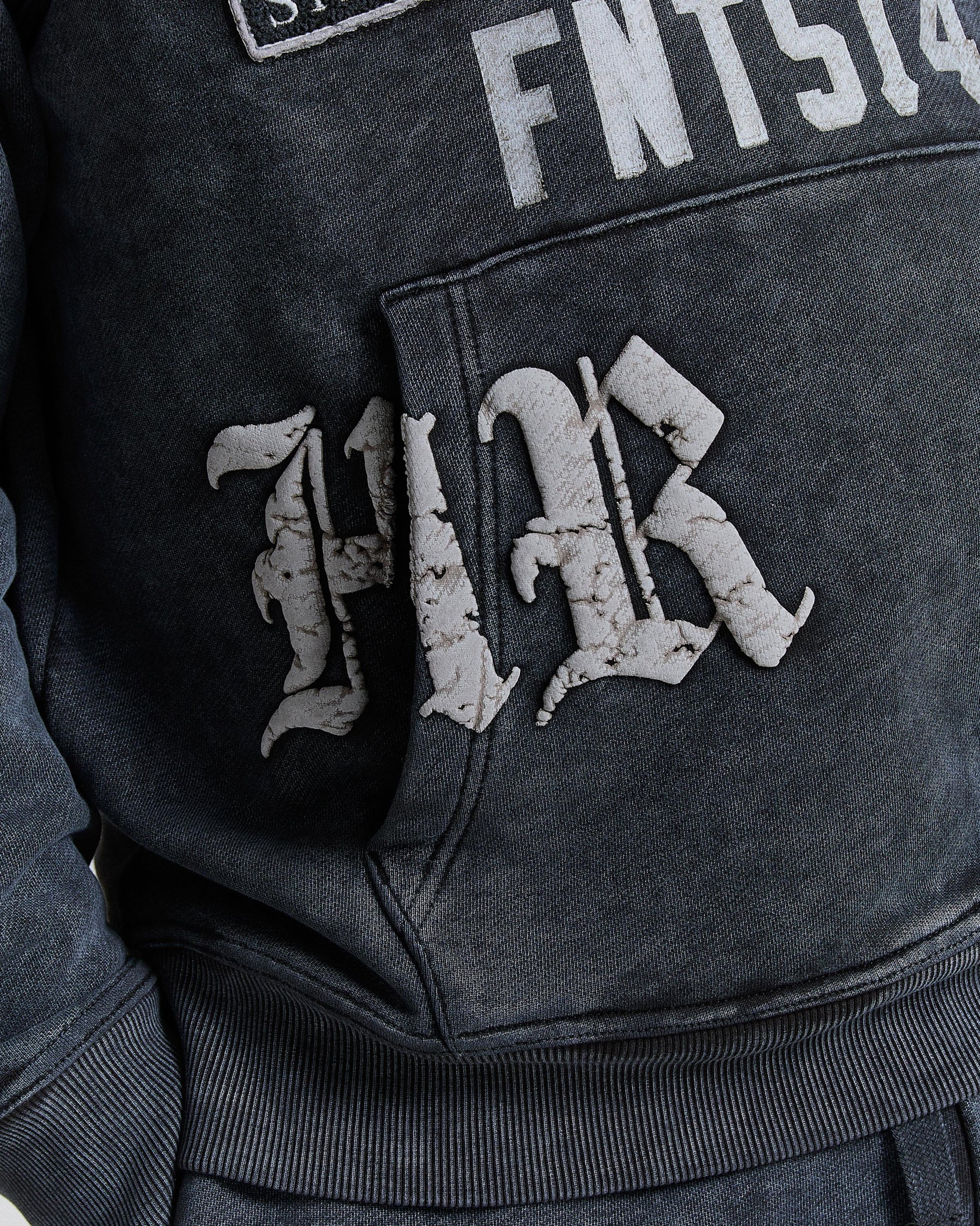Close-up of a dark gray hoodie with embroidered lettering on the chest and back.