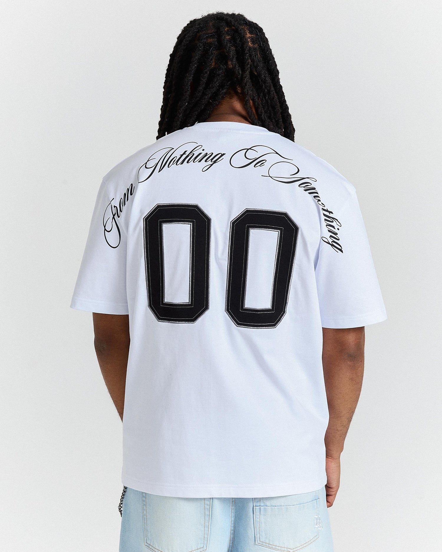 Person wearing a white t-shirt with black text and numbers on the back, standing against a plain background.