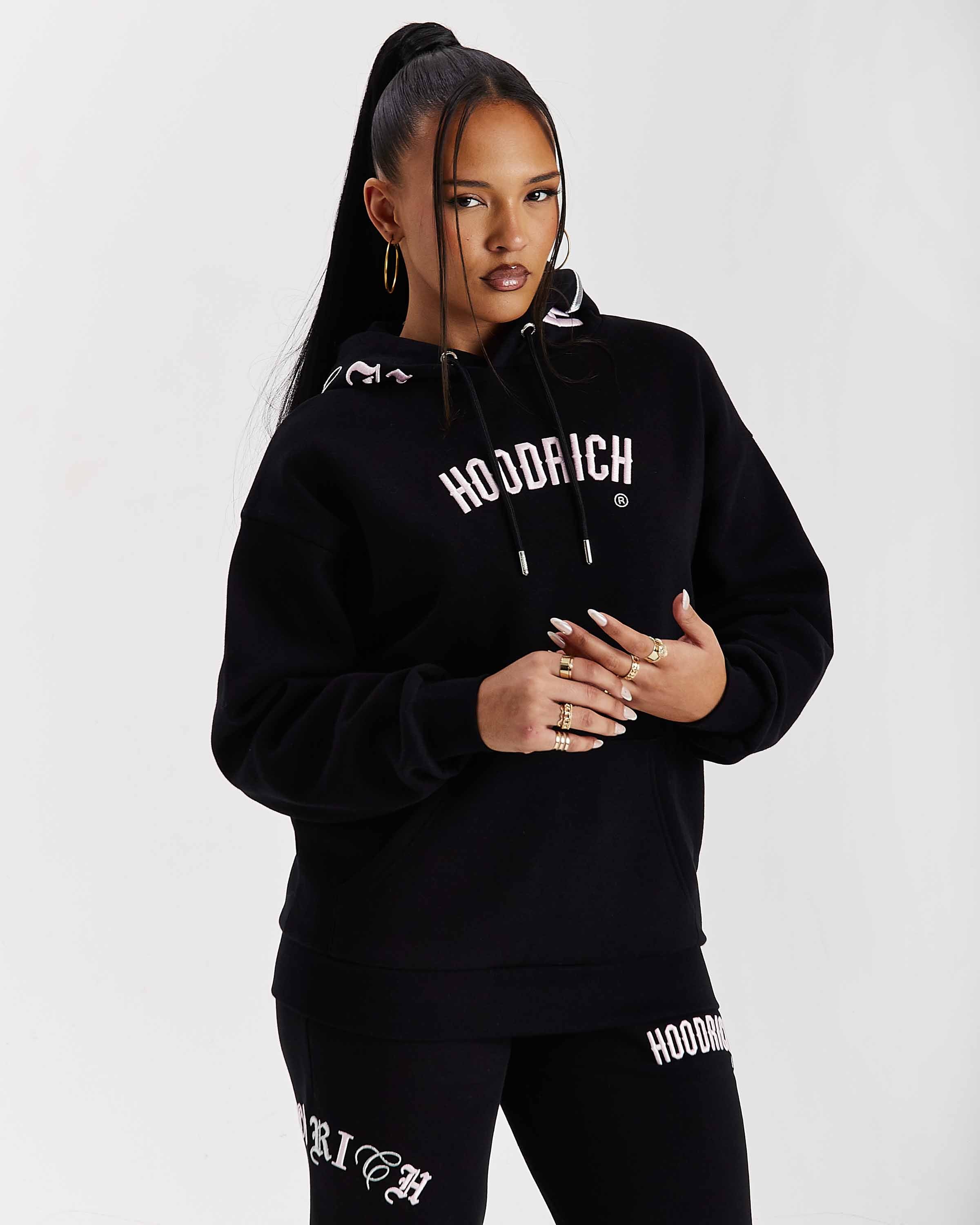 Person wearing a black 'Hoodrich' hoodie and pants on a white background