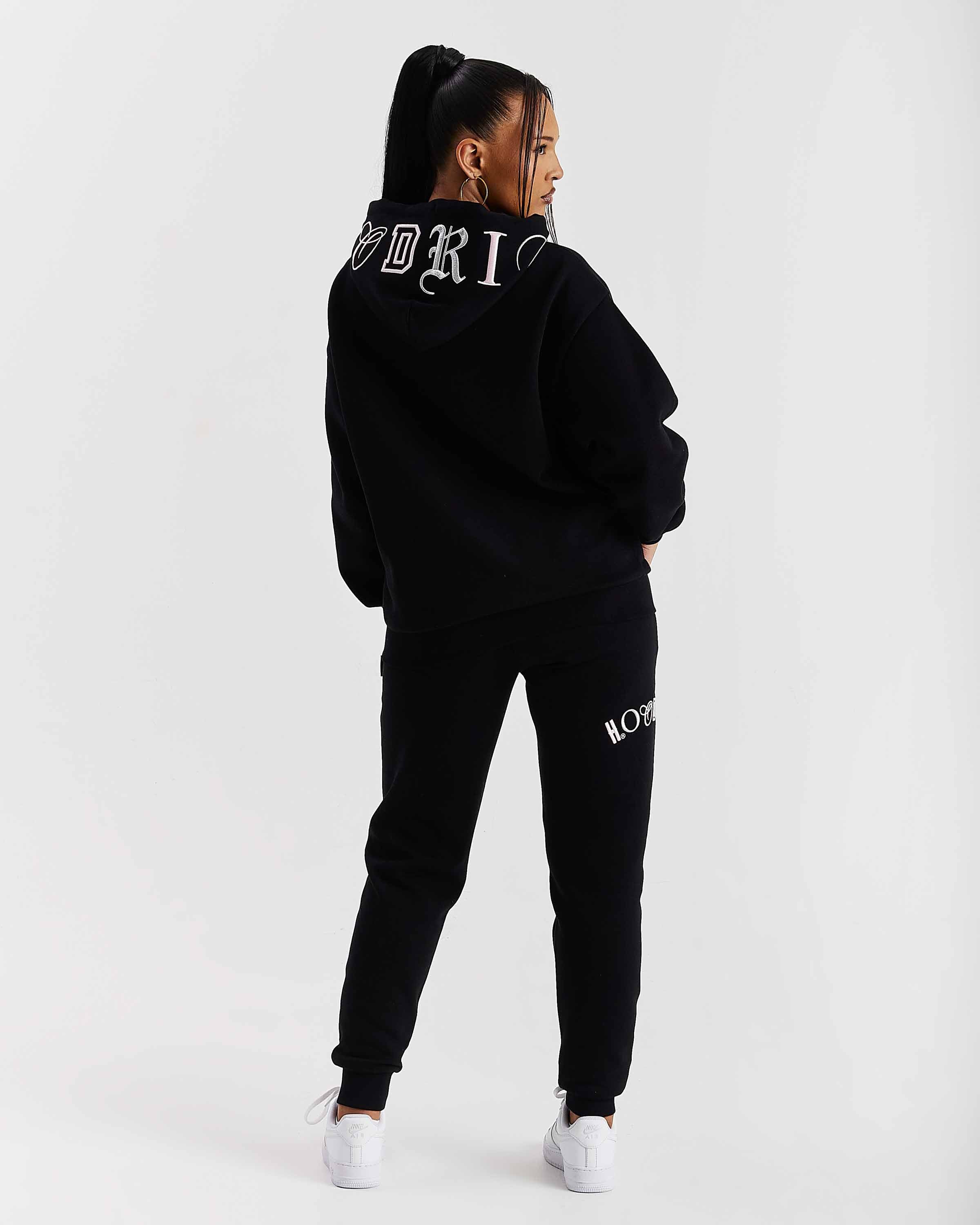 Person wearing a black tracksuit with branding on a white background