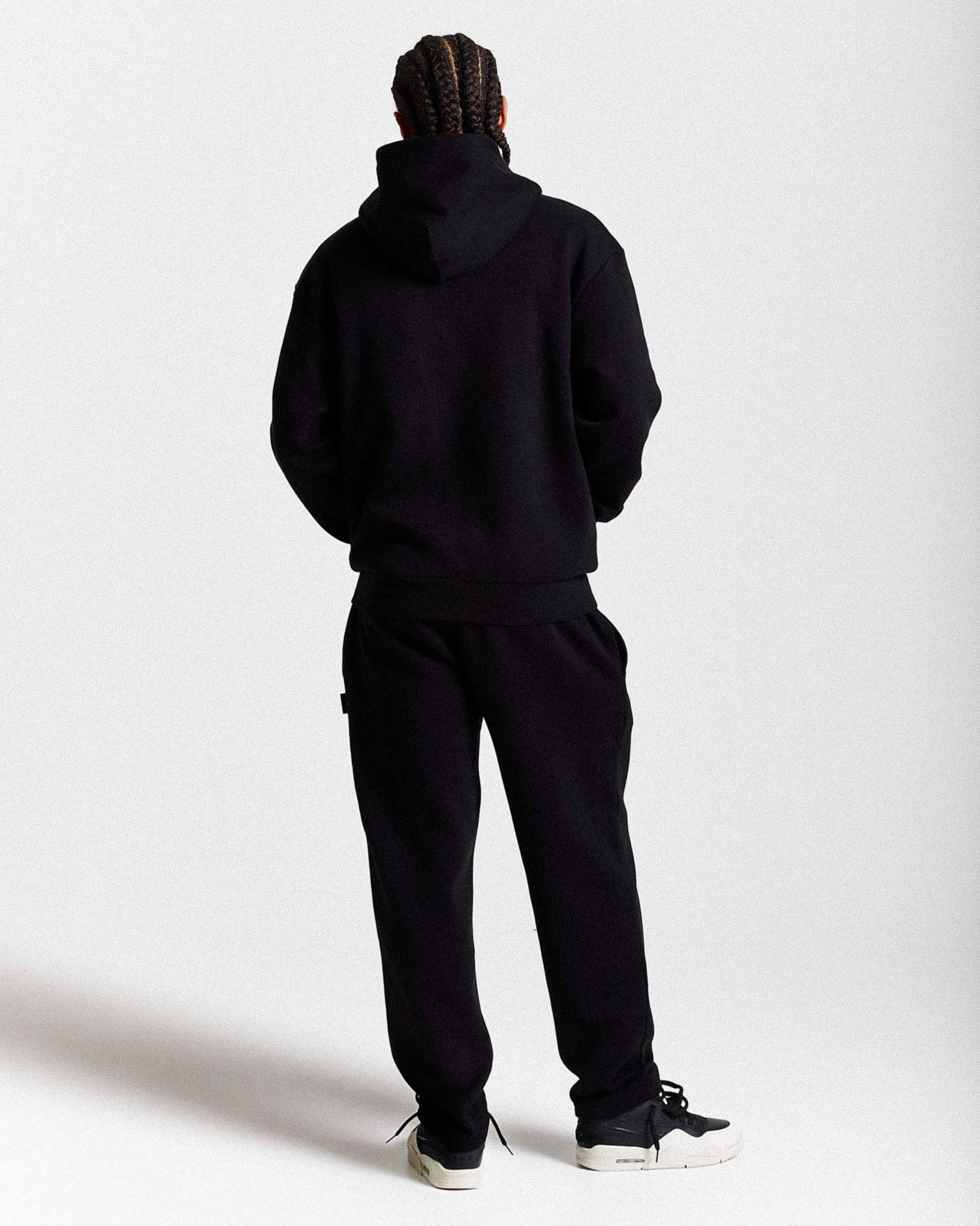 Person wearing a black tracksuit on a white background
