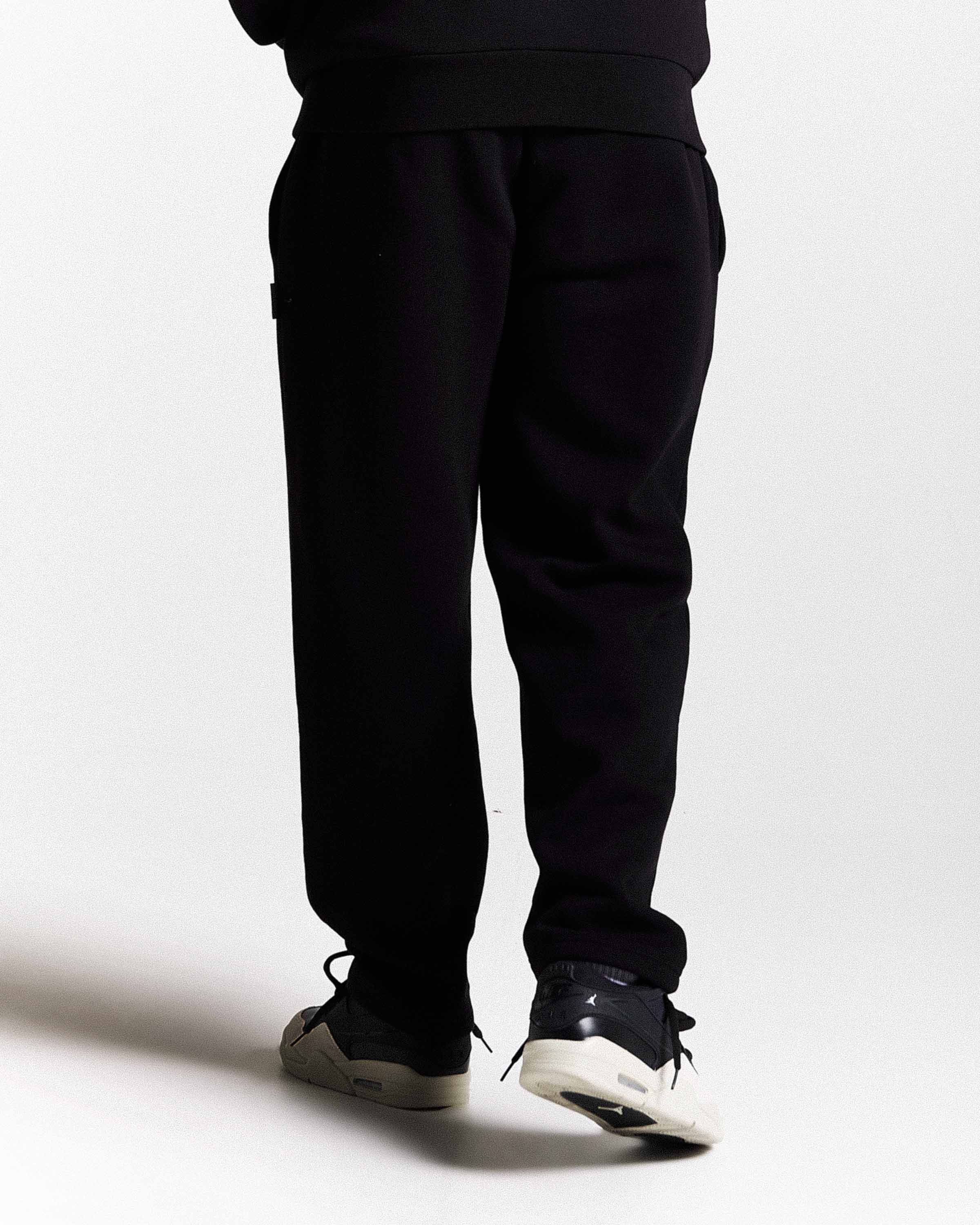 Person wearing black pants and shoes on a white background