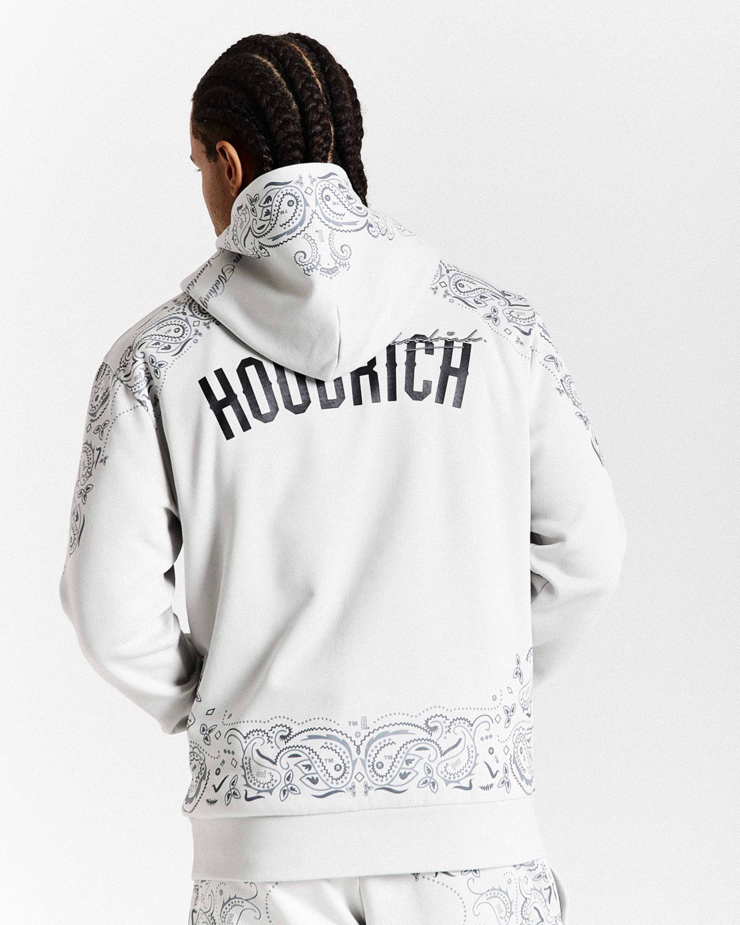 Person wearing a white hoodie with intricate patterns and 'Hoodrich' branding on the back.